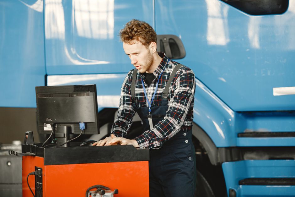 Technicien GB Trucks réalisant un diagnostic électronique devant un poids lourd